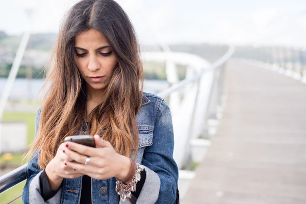 Young brunette woman looking her smart phone — Stock Photo, Image