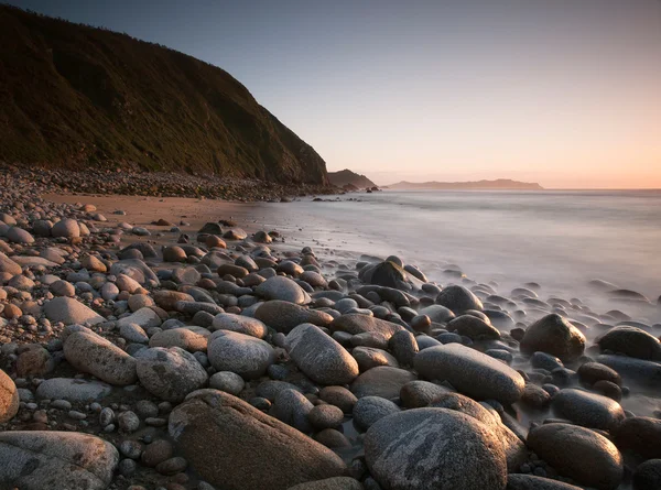 Rotsachtige strand bij zonsondergang. — Stockfoto