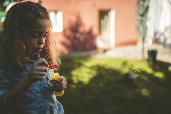 Little girl blowing soap bubbles outdoors — Stock Photo, Image