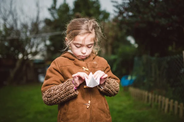 Little girl playing with a piece of paper outdoors — Stock Photo, Image