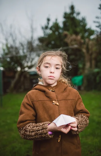 Little girl with serious expression playing with a piece of pape — Stock Photo, Image