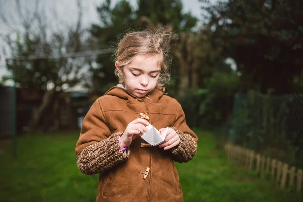 Little girl playing with a piece of paper outdoors — Stock Photo, Image