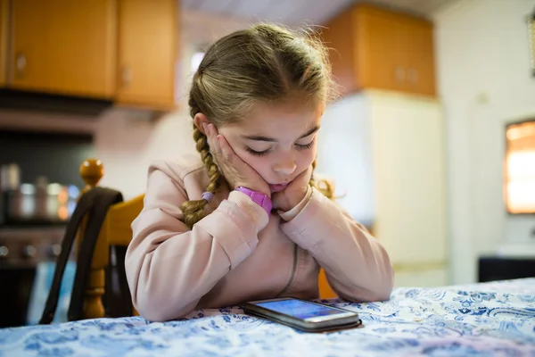 Pigtails seyir bir akıllı telefon ile küçük sarışın kız