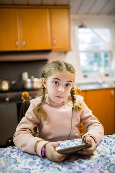 Little blonde girl with an smart phone looking at camera. — Stock Photo, Image