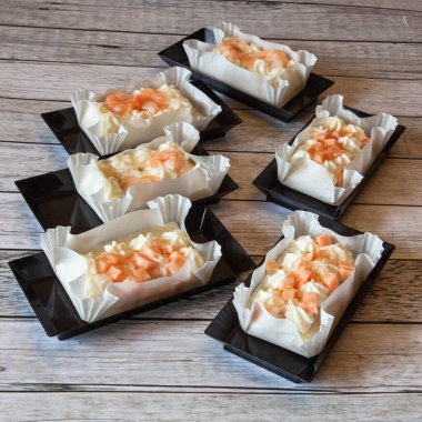 Somon ve karides kanepeleri dikdörtgen siyah plastik tepsilerde iştah açıcı, doğal ışık.