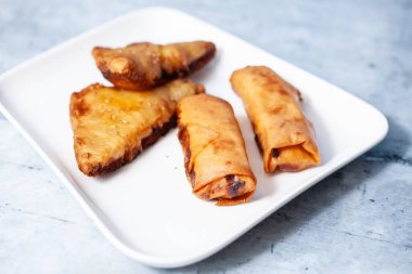 Beyaz tabaklar ve mavi-gri arka planda Çin mutfağı yemekleri.