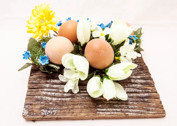 Eggs on a wooden table with cloth flowers — Stock Photo, Image