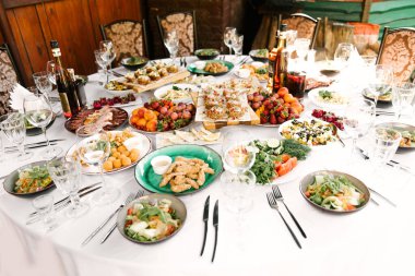 Lezzetli yiyecek ve atıştırmalıklarla dolu yuvarlak masa ziyafeti, güzel bir ortam, yemek servisi, temiz havada tatil.