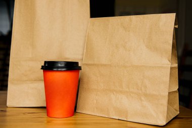 Yiyecek dolu el çantası ve kahve ya da çay dolu kağıt bardak. Mavi arkaplanda paket yemek kavramı ve kopyalama alanı.