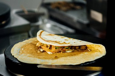 Krep kızartılmış ve büyük bir demir roti makinesi tavasında pişiriliyor. Geleneksel Hint sokak yemekleri. Muzlu, jambonlu ve peynirli Tayland gözlemesi .