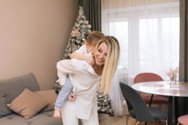 Güzel, genç bir anne, bebeğiyle birlikte gülüyor ve gülümsüyor.