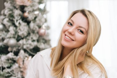 Güzel, genç, sarışın, gülümseyen kız yeni yıl için evi dekore ediyor.