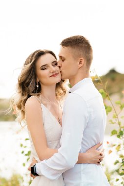 Birbirlerine aşık güzel bir çift, bir erkek ve bir kadın, gün batımında mavi bir göl ve kum kenarında öpüşürler. Sahilde deniz tatili, gün batımı, sabah, balayı, tropik hava, okyanus, kız, ilişki..