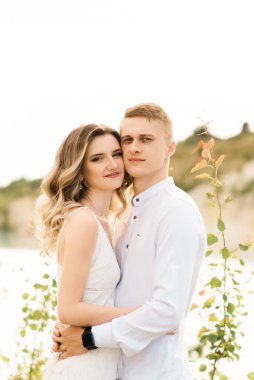 Birbirlerine aşık güzel bir çift, bir erkek ve bir kadın, gün batımında mavi bir göl ve kum kenarında öpüşürler. Sahilde deniz tatili, gün batımı, sabah, balayı, tropik hava, okyanus, kız, ilişki..