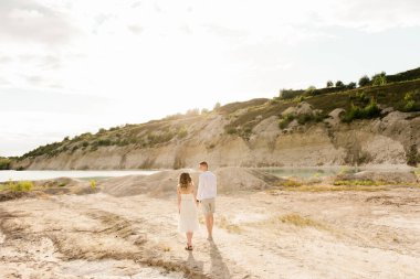 Birbirlerine aşık güzel bir çift, bir erkek ve bir kadın, gün batımında mavi bir göl ve kum kenarında öpüşürler. Sahilde deniz tatili, gün batımı, sabah, balayı, tropik hava, okyanus, kız, ilişki..