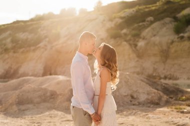 Birbirlerine aşık güzel bir çift, bir erkek ve bir kadın, gün batımında mavi bir göl ve kum kenarında öpüşürler. Sahilde deniz tatili, gün batımı, sabah, balayı, tropik hava, okyanus, kız, ilişki..