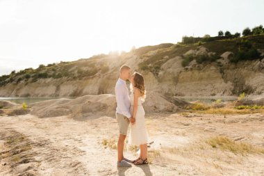 Birbirlerine aşık güzel bir çift, bir erkek ve bir kadın, gün batımında mavi bir göl ve kum kenarında öpüşürler. Sahilde deniz tatili, gün batımı, sabah, balayı, tropik hava, okyanus, kız, ilişki..