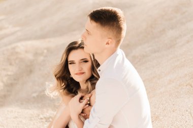 Birbirlerine aşık güzel bir çift, bir erkek ve bir kadın, gün batımında mavi bir göl ve kum kenarında öpüşürler. Sahilde deniz tatili, gün batımı, sabah, balayı, tropik hava, okyanus, kız, ilişki..