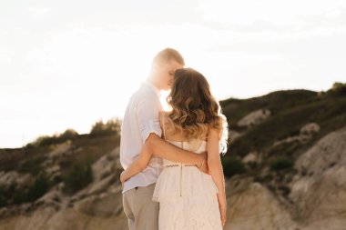 Birbirlerine aşık güzel bir çift, bir erkek ve bir kadın, gün batımında mavi bir göl ve kum kenarında öpüşürler. Sahilde deniz tatili, gün batımı, sabah, balayı, tropik hava, okyanus, kız, ilişki..
