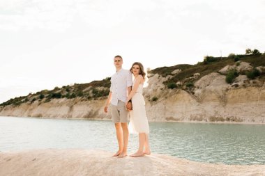 Birbirlerine aşık güzel bir çift, bir erkek ve bir kadın, gün batımında mavi bir göl ve kum kenarında öpüşürler. Sahilde deniz tatili, gün batımı, sabah, balayı, tropik hava, okyanus, kız, ilişki..