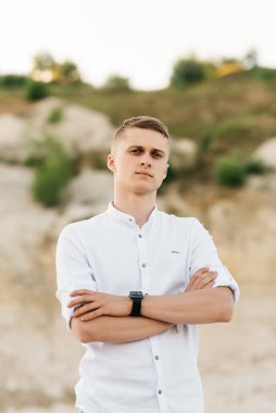 Güzel genç adam mavi bir göl ve gün batımında kumla dünyayı dolaşır.