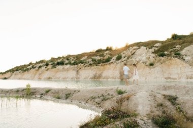 Birbirlerine aşık güzel bir çift, bir erkek ve bir kadın, gün batımında mavi bir göl ve kum kenarında öpüşürler. Sahilde deniz tatili, gün batımı, sabah, balayı, tropik hava, okyanus, kız, ilişki..