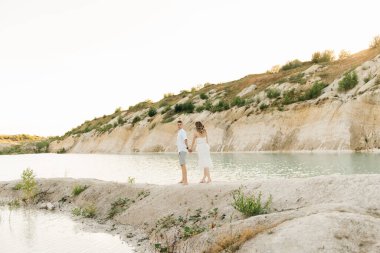 Birbirlerine aşık güzel bir çift, bir erkek ve bir kadın, gün batımında mavi bir göl ve kum kenarında öpüşürler. Sahilde deniz tatili, gün batımı, sabah, balayı, tropik hava, okyanus, kız, ilişki..