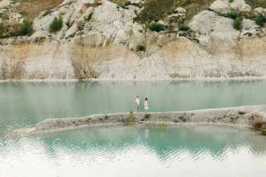 Birbirlerine aşık güzel bir çift, bir erkek ve bir kadın, gün batımında mavi bir göl ve kum kenarında öpüşürler. Sahilde deniz tatili, gün batımı, sabah, balayı, tropik hava, okyanus, kız, ilişki..