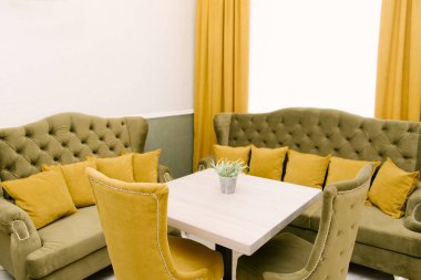 Sıcak bir kafe, boş hardal ve zeytin rengi masalar.