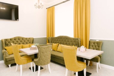 Sıcak bir kafe, boş hardal ve zeytin rengi masalar.