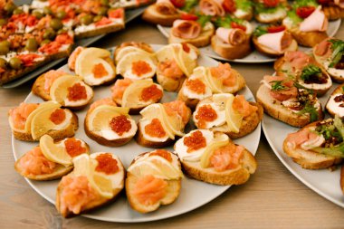Lezzetli baharatlı İtalyan atıştırmalıkları, ya da kızarmış ekmek dilimleri, fesleğen, kırmızı balık, ahşap bir tahtada jambon ile süslenmiş.