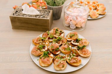 Lezzetli baharatlı İtalyan atıştırmalıkları, ya da kızarmış ekmek dilimleri, fesleğen, kırmızı balık, ahşap bir tahtada jambon ile süslenmiş.