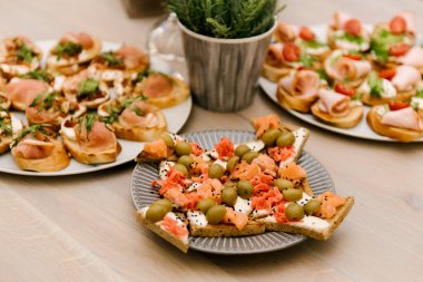 Lezzetli baharatlı İtalyan atıştırmalıkları, ya da kızarmış ekmek dilimleri, fesleğen, kırmızı balık, ahşap bir tahtada jambon ile süslenmiş.