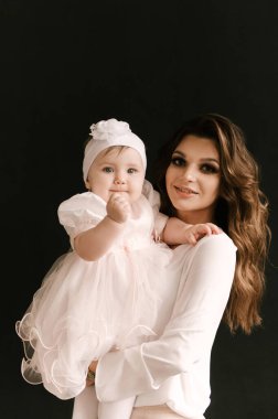 Siyah arka planda gülümseyen güzel, genç bir anne.