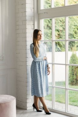 Pencerenin yanındaki mavi elbiseli çekici genç kız.