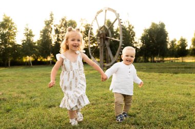 Güneşli bir günde küçük tatlı kız kardeşiyle dışarıda oynuyor.