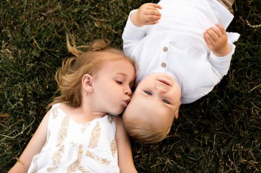 Güneşli bir günde küçük tatlı kız kardeşiyle dışarıda oynuyor.