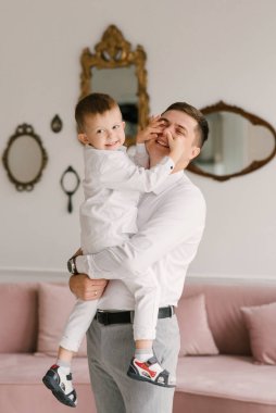 Güzel, genç baba ve oğul sarılıp evde şık kıyafetler giyip oynuyorlar.