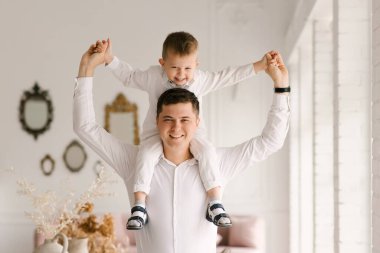 Güzel, genç baba ve oğul sarılıp evde şık kıyafetler giyip oynuyorlar.