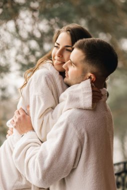 Genç, güzel, mutlu, yeni evliler. Beyaz banyo cüppeli bir adamla bir kadın evin balkonunda gülümsüyor ve sarılıyorlar.