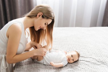 Sevgi dolu bir anne yeni doğmuş bebeğini evde taşır. Kollarında uyuyan bir bebeği tutan mutlu bir annenin portresi. Anne, 4 aylık küçük kızına sarılıyor.