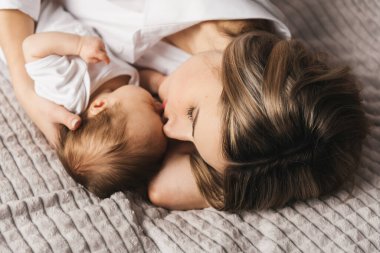 Sevgi dolu bir anne yeni doğmuş bebeğini evde taşır. Kollarında uyuyan bir bebeği tutan mutlu bir annenin portresi. Anne, 4 aylık küçük kızına sarılıyor.