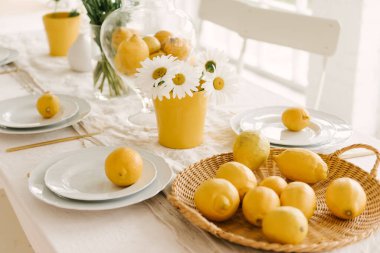 Bir sürü limon ve papatya ile güzel servis edilen bahar beyaz masası..