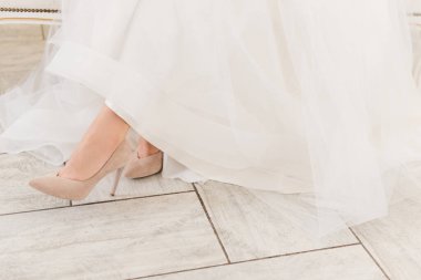 Gelinin ayaklarında bej rengi topuklular, arka planda hafif bir arka plan, kadın ayakkabıları.