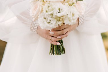 Pastel renkte düğün buketi güllerin, mutluluğun, şakayıkların, karanfillerin ve okaliptüslerin ellerinde..