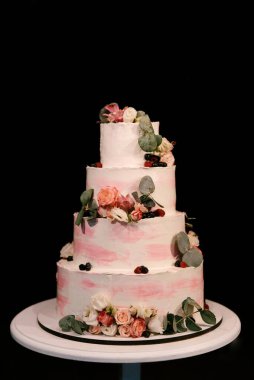 Lüks düğün, çiçeklerle süslenmiş beyaz pasta, arka planda gece çekilmiş fotoğraf.