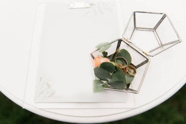 Cam bir kutuda evlilik yüzükleri kayıt töreni için hazırlanır ve çiçeklerle süslenir.