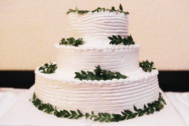 Lüks düğün, çiçeklerle süslenmiş beyaz pasta, arka planda gece çekilmiş fotoğraf.