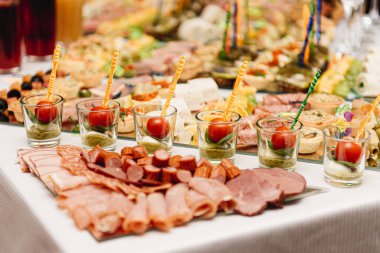 Güzel dekore edilmiş yemek masası. Hamburger, profiterol, salata ve soğuk atıştırmalıklarla. Masada çeşitli lezzetli atıştırmalıklar var.