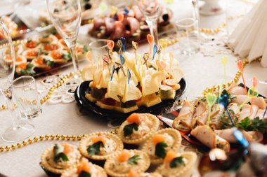 Güzel dekore edilmiş yemek masası. Hamburger, profiterol, salata ve soğuk atıştırmalıklarla. Masada çeşitli lezzetli atıştırmalıklar var.